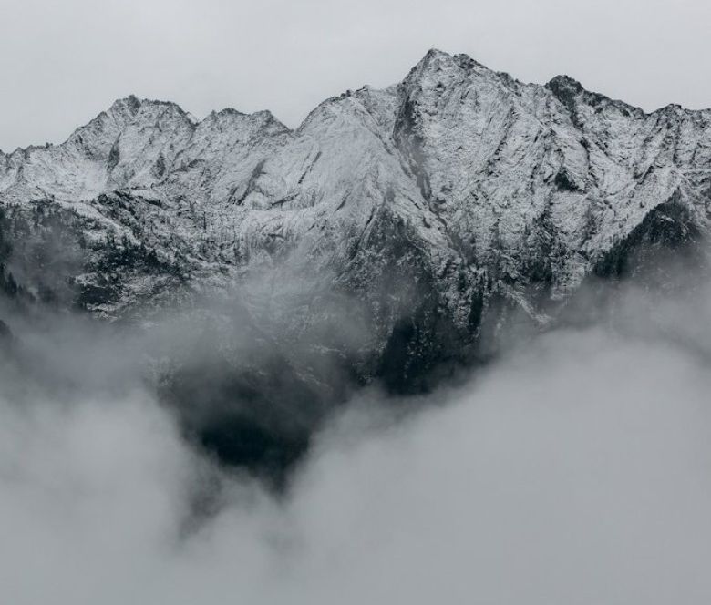 A snowy mountain rising above clouds